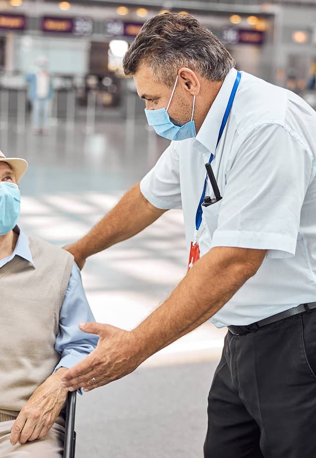 Airport staff assisting an elderly person.